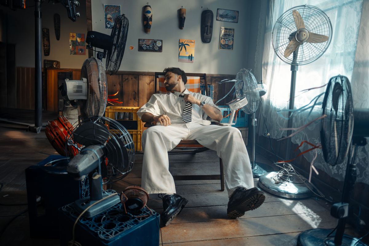 A man wiping sweat from his forehead in a hot home because the air conditioner is running but not cooling